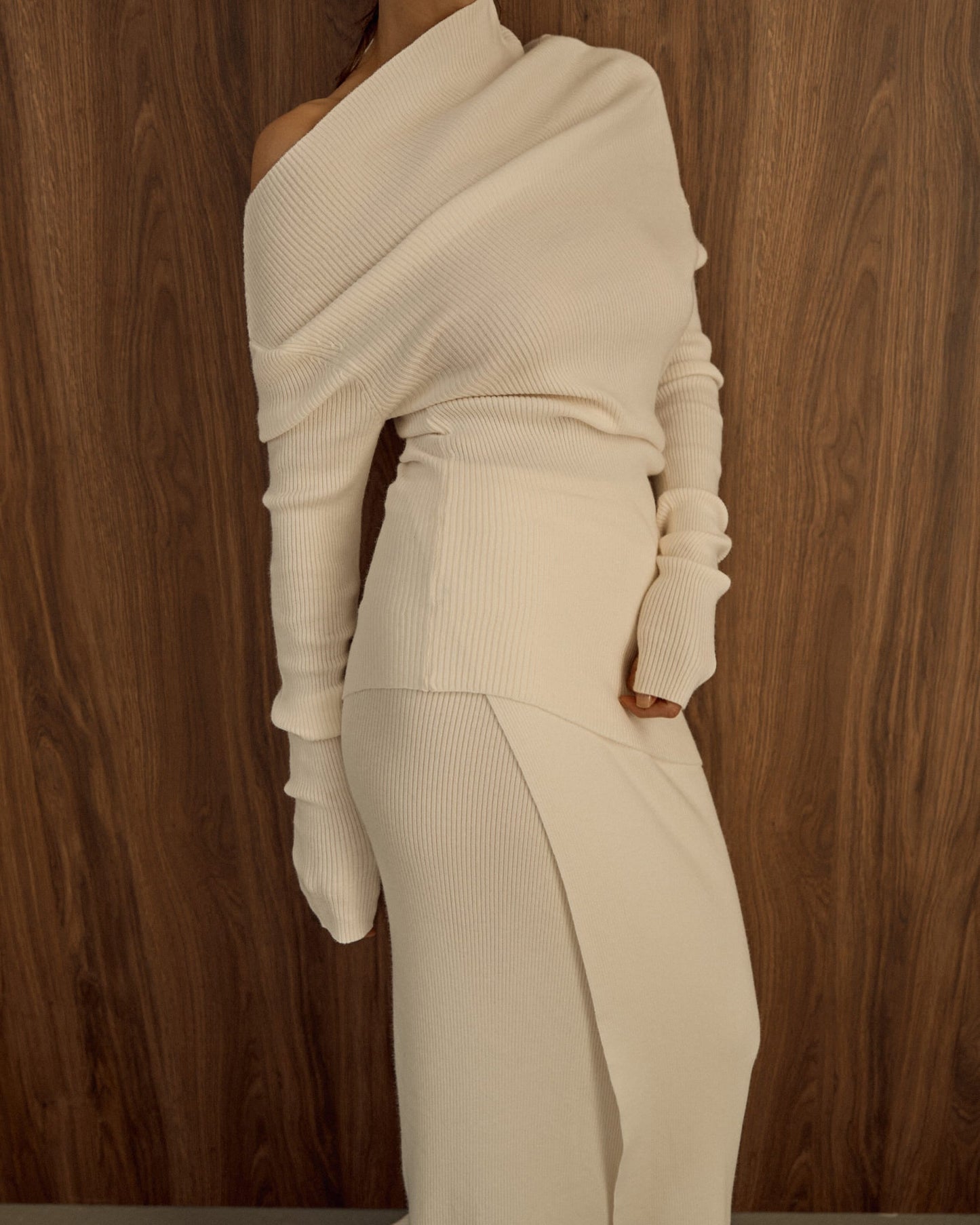 Avani Set in a creamy off-white ribbed knit fabric. The outfit features a long-sleeve asymmetrical draped top paired with a sleek matching skirt, minimalist, elegant aesthetic.