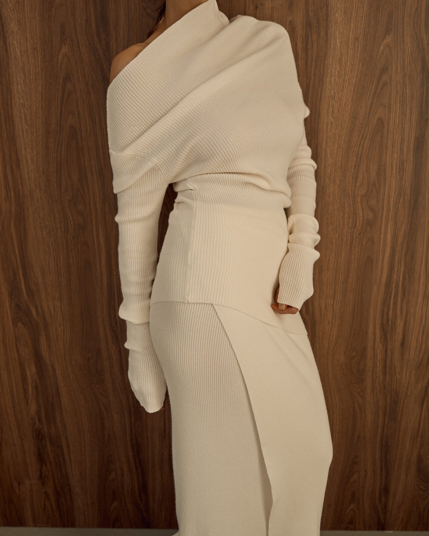 Avani Set in a creamy off-white ribbed knit fabric. The outfit features a long-sleeve asymmetrical draped top paired with a sleek matching skirt, minimalist, elegant aesthetic.