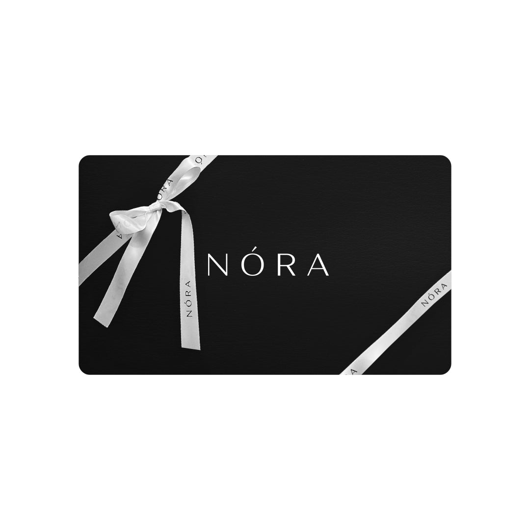 The NÓRA Gift Card comes in a sophisticated black rectangular box with rounded corners. "NÓRA" is showcased in white at the center, complemented by a white ribbon featuring tied bows, each displaying "NÓRA," epitomizing timeless style and elegance.